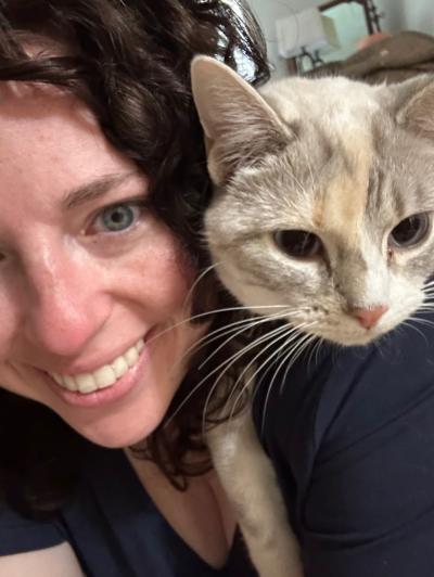 Maycee smiling with a cat on her shoulder